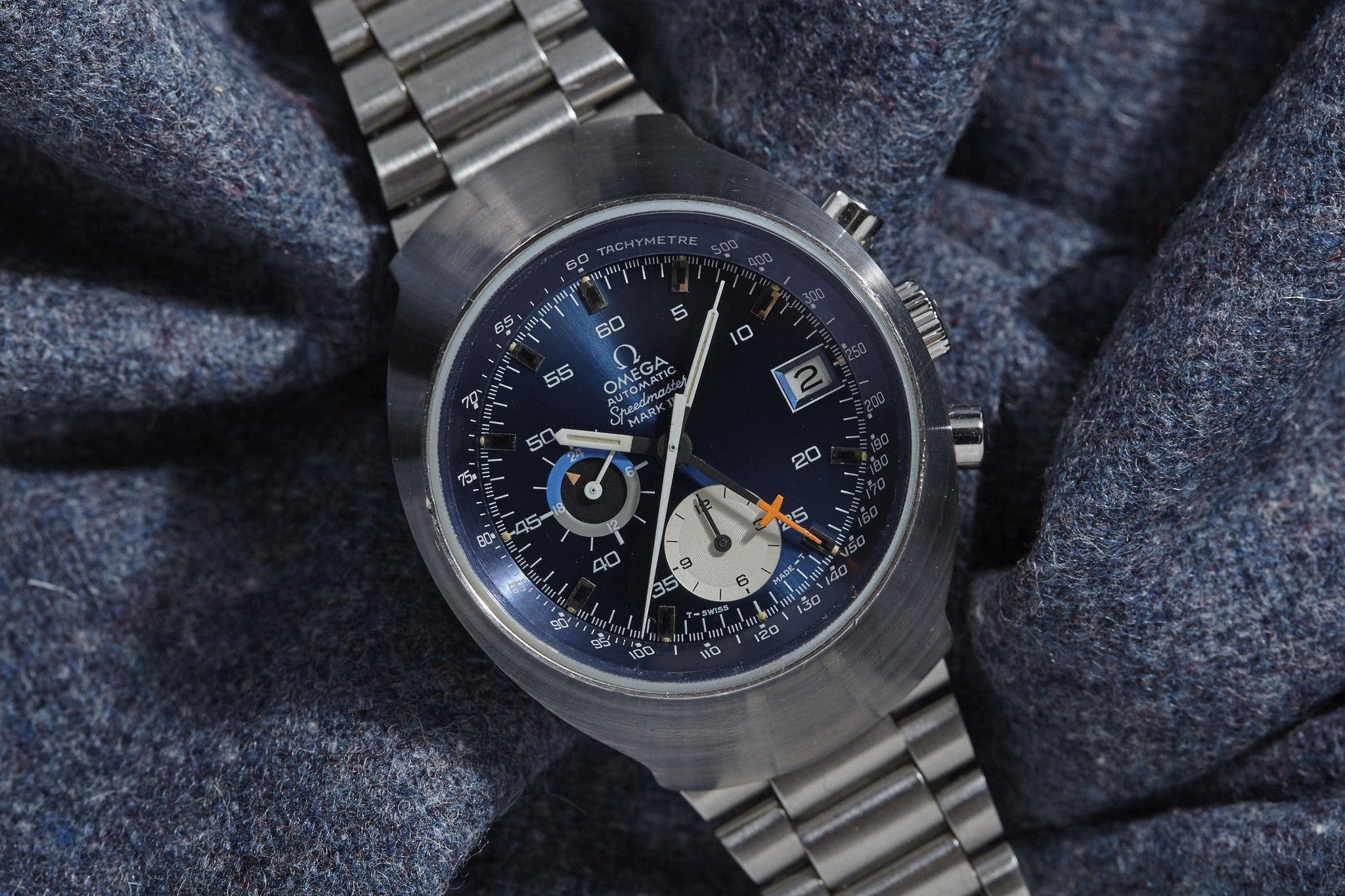 A vintage Omega Speedmaster Mark chronograph on a tweed background